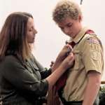 Amanda attaching Eagle medal to Devyn’s uniform
