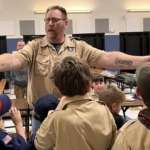 Cubmaster MacFarland passing out Pinewood Derby casrs